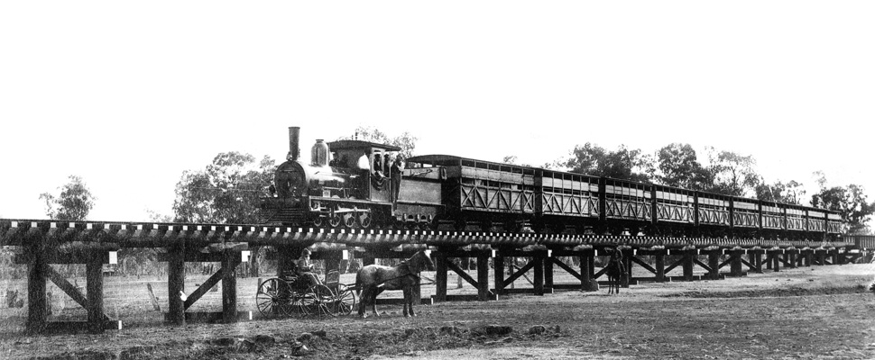The photograph shows B12 class locomotive No. 30, on a low, timber trestle bridge crossing Bungil Creek, near Roma, Queensland, full image description is available below.
