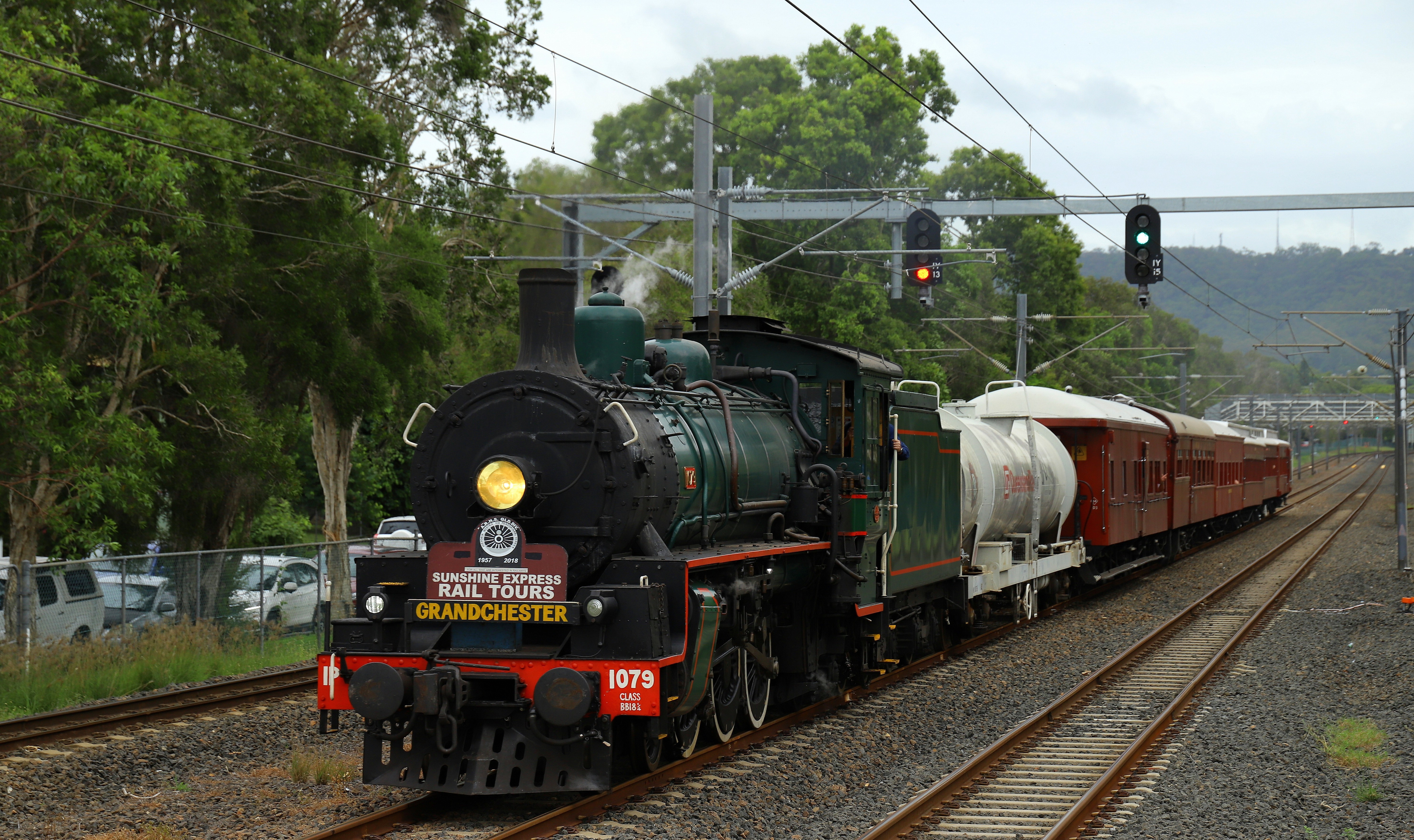 Green steam train on track pulling old carriages
